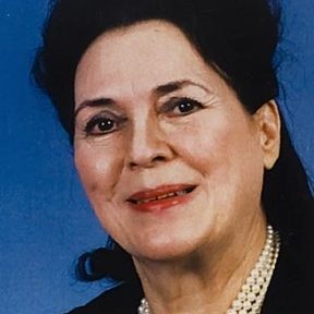 A woman with curly hair and wearing a necklace.